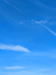 Blue Skies with wispy chemtrail aeroplane lines and fluffy white clouds