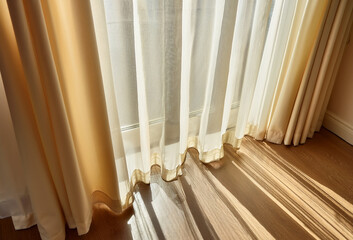 Soft morning light filters through elegant sheer curtains, casting gentle shadows on the wooden floor.