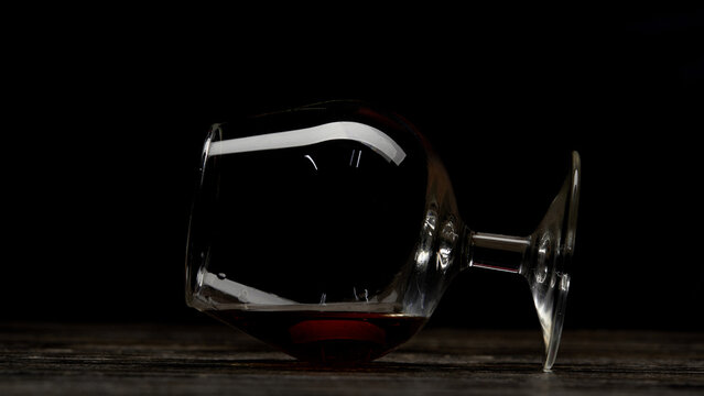 A Glass of Red Wine Spilled on a Wooden Surface, Creating a Unique Visual Contrast Against a Black Background