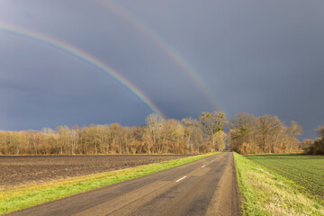 Serene Rural Road with Double Rainbow in Sky