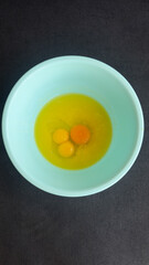 Delicious and Freshly Cracked Eggs in a Light Blue Bowl Ready for Cooking or Baking Against a Dark Background for a Stunning Visual Presentation