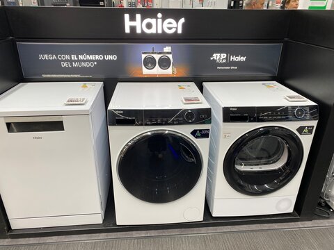 Palma De Mallorca, Spain - July 04, 2025: Haier appliances display featuring washing machine, dryer, and refrigerator in a modern retail store showcasing innovative home technology