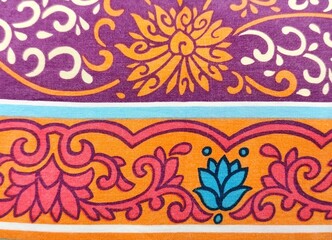 Background view of a vibrant textile pattern featuring floral and scroll motifs in purple, orange,...