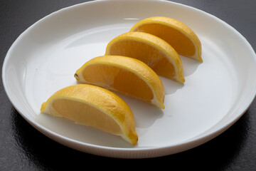 Lemon slices on white plate. Freshness concept, making lemonade with lemon slices. Summer cold...