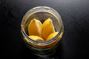 Lemon slices in a glass in a jar. Freshness concept, Lemonade with lemon slices in a jar on a black background. Summer cold refreshing drinks.