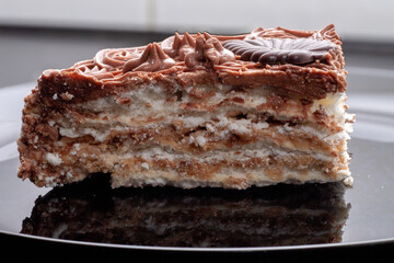 A slice of delicious protein chocolate cake in a cut on a black plate. Dessert on a plate.