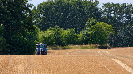 New Holland tractor waiting in harvested barley field at Lauterbach, Germany