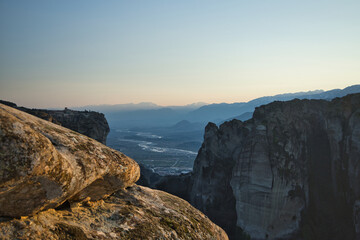 Meteora’s monasteries perch on rocky cliffs, lit by soft afternoon winter sun, blending nature...