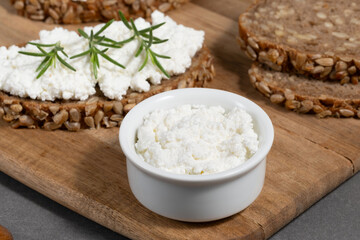Delicious rye bread topped with creamy cheese and fresh herbs on a rustic wooden board