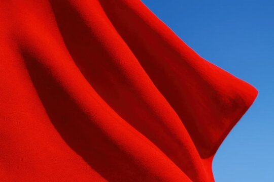 A vibrant red flag waves against a clear blue sky, symbolizing strength and unity