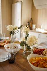 A vase of white roses decorates the table with food and cutlery.