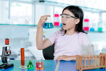 Amazed young girl observing chemical reaction in science lab during school experiment