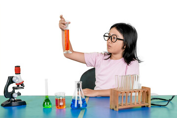 Focused young girl examining liquid in graduated cylinder during science experiment