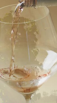 Composite of white wine being poured into glass over vineyard background