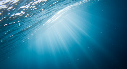 Underwater sunlight rays illuminating ocean surface in blue hues  