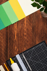 Workspace for paper crafts. Black cutting mat, colored paper, pencils, scissors, ruler, glue. Space...