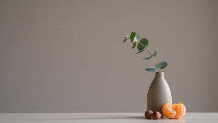 Minimalist Still Life: Eucalyptus Sprig in Grey Vase with Mandarin and Chestnuts on Neutral Background