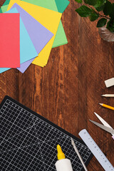 Workspace for paper crafts. Black cutting mat, colored paper, pencils, scissors, ruler, glue. Space...