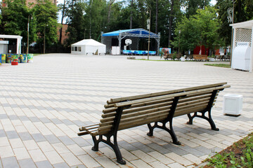 Long wooden bench in the town square, rear view.