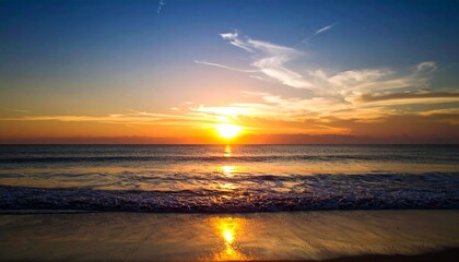 Fototapeta premium A majestic golden sunset over the ocean horizon, casting a tranquil reflection on the peaceful beach waves.