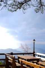 Wooden table outdoor on terrace with classic and vintage black iron street light in valley mountain and blue sky view of local restaurant in countryside of Thailand