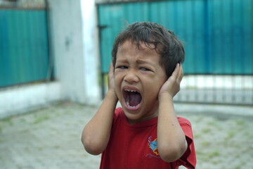 a toddler is covering his ears because he hears a loud noise