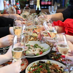 The girls make a toast with glasses of champagne at the festive table.