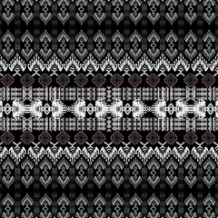 Intricate black and white textile pattern featuring geometric shapes and floral motifs, creating striking visual effect
