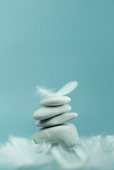Balanced Stones and white feather on blue background, Calm and stable mindset, inner peace and emotional steadiness , Vertical image