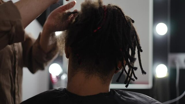 A skilled stylist is meticulously working on brand new dreadlocks within a bright and inviting salon setting