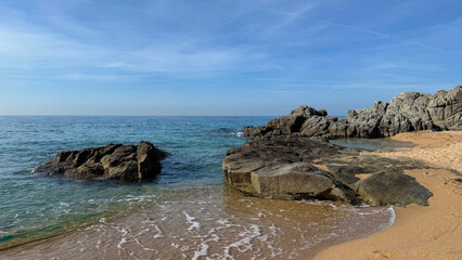 A sunny view of Fenals Beach in Lloret de Mar, Costa Brava, featuring golden sand, calm...
