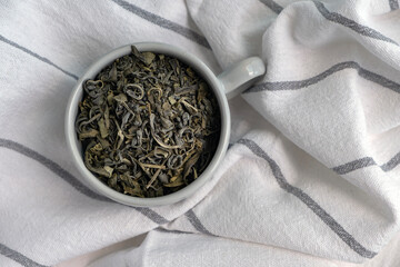 Dry green tea leaves in a cup. Closeup