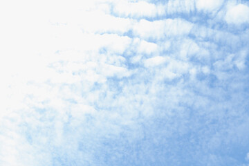 Soft clouds drift gently across a bright blue sky on a serene afternoon