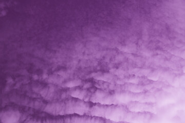 Clouds swirl in hues of purple at twilight illuminating the evening sky