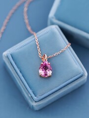 A delicate pink pear gemstone necklace sits in a blue box