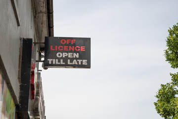 Neon shop sign reading "Off Licence Open Till Late," with red and white text. Although illuminated, the photo was taken in daylight outside the store.