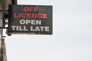 Neon shop sign reading "Off Licence Open Till Late," with red and white text. Although illuminated, the photo was taken in daylight outside the store.