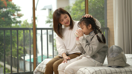 A girl in fencing gear with their mother preparing milk and sports equipment before practicing...