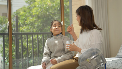 A girl in fencing gear with their mother preparing sports equipment