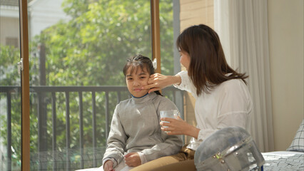 A girl in fencing gear with their mother preparing milk and sports equipment before practicing...