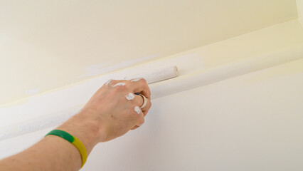 Painting a wall at home in a hard-to-reach place with a small roller