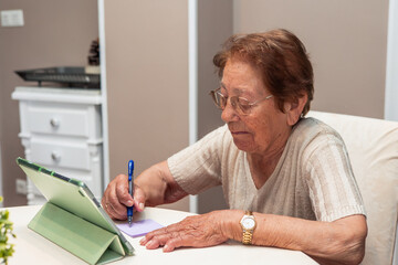 Elderly Woman Engaging with Digital Tablet and Writing