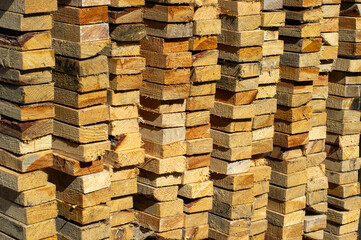  stacked piles of rough-cut lumber with varying shades of natural wood tones.