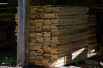 stack of firewoodStacks of cut wooden planks are piled under a sheltered outdoor structure.