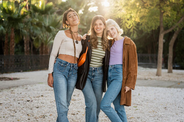 Three young women in 70s inspired retro fashion, friends posing for a lookbook outdoors.