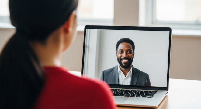 Smiling African-American man on a video call with colleagues, seen on laptop screen.