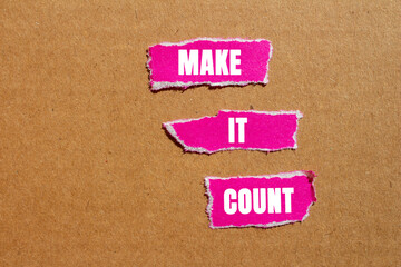 Make it count message written on ripped torn pink paper pieces on cardboard background. Conceptual...