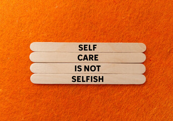 Self care is not selfish message written on wooden sticks on orange background. Conceptual self...