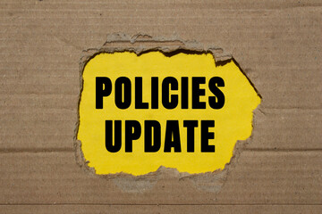 Policies update message written on ripped torn cardboard paper on yellow background. Conceptual...