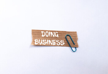 Doing business message written on ripped torn brown paper piece on white background. Conceptual...